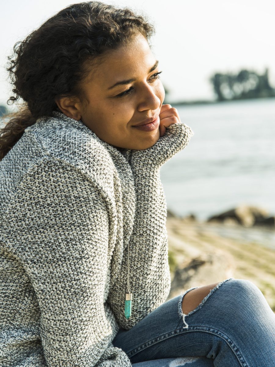 Smiling young woman sitting by the riverside